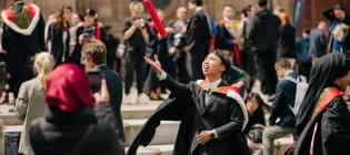 A graduate celebrates outside McEwan Hall
