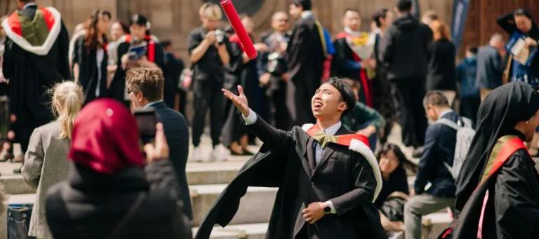 A graduate celebrates outside McEwan Hall