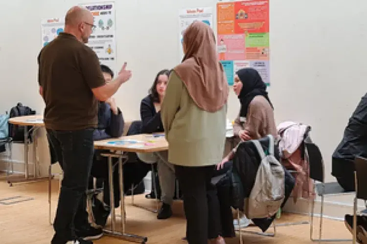 A group of students and university staff discussing their proposed ideas.
