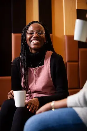 Image of student smiling and drinking coffee